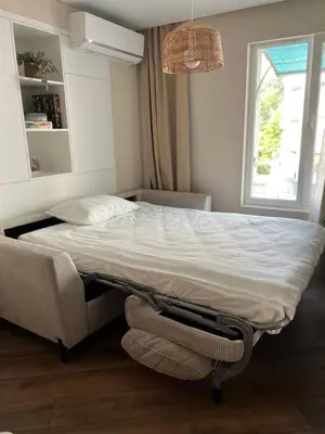 a bedroom with a bed and a couch and a window at Lazur Beach Residence - 10min walk to beach in Burgas City