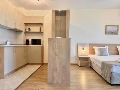a bedroom with a large bed and a kitchen at Sea View Allure Studio with Balcony in Primorsko