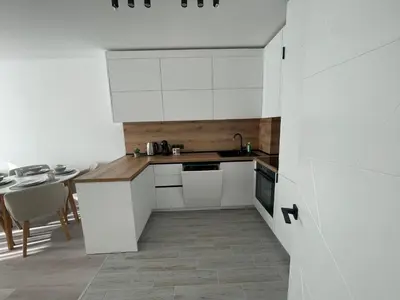 a kitchen with white cabinets and a table at Сарафово Family in Burgas City