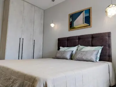 a bedroom with a large bed with a brown headboard at Ika Apartment Central in Burgas City