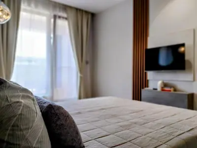 a hotel room with a bed and a television at Ika Apartment Central in Burgas City