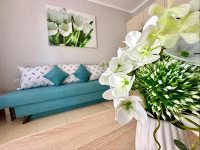 a living room with a blue couch and white flowers at Jasmine - Menada Apartments in Sunny Beach