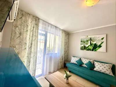 a living room with a green couch and a window at Jasmine - Menada Apartments in Sunny Beach