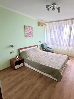 a bedroom with a bed and a chair and a window at PanoramaView Lazur in Burgas City