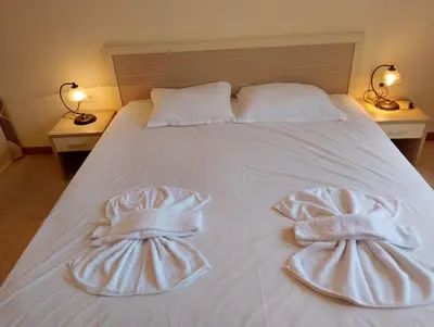 a white bed with two towels on it with two lamps at 2 Room Apartment with Poolview Royal Sun in Sunny Beach