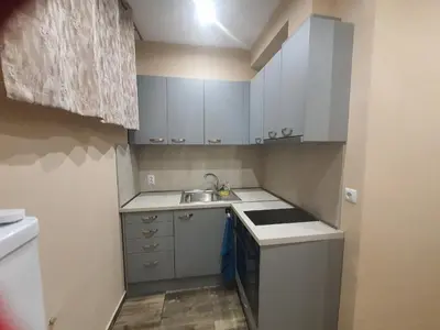 a small kitchen with white cabinets and a sink at Студио Морски бриз in Pomorie