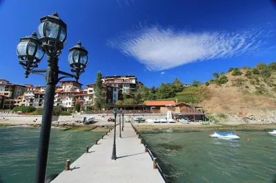 a pier with street lights next to a body of water at Аpartment in the Garden of Eden in Sveti Vlas