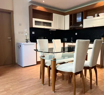 a dining room with a glass table and white chairs at Аpartment in the Garden of Eden in Sveti Vlas