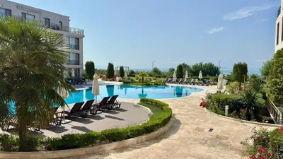 a swimming pool in a resort with chairs and a building at Апартамент Панорама, двустаен, малък, първа линия, гледка море, DIAMOND BEACH, Сарафово in Burgas City