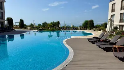 a large swimming pool with lounge chairs next to a building at Апартамент Панорама, двустаен, малък, първа линия, гледка море, DIAMOND BEACH, Сарафово in Burgas City