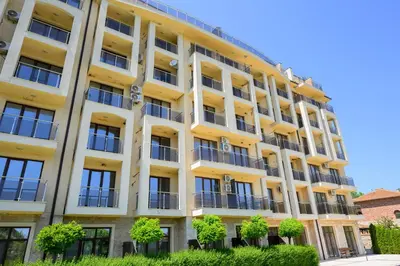 a yellow building with trees in front of it at Azur Properties ap51 in Shkorpilovtsi