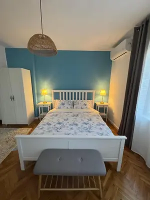 a bedroom with a white bed with a blue wall at Studio by the sea in Primorsko