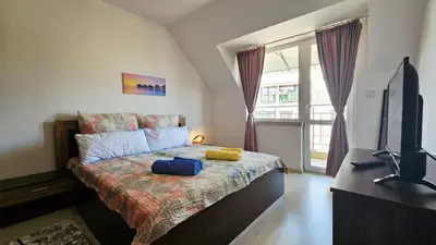a bedroom with a bed and a tv and a window at Апартамент Комфорт in Varna City