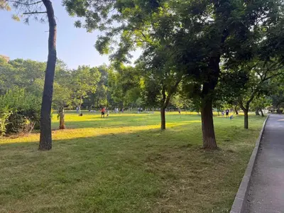 a park with trees and people walking in the grass at Lazzuro 7 in Burgas City
