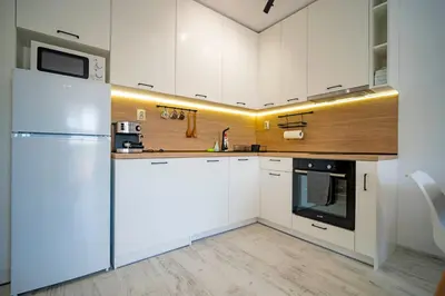 a kitchen with white cabinets and a refrigerator at Next to Harmanite Beach - 1 BD Flat with Own Parking spot by Flat Mаnager in Sozopol