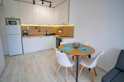 a small kitchen with a wooden table and white chairs at Next to Harmanite Beach - 1 BD Flat with Own Parking spot by Flat Mаnager in Sozopol