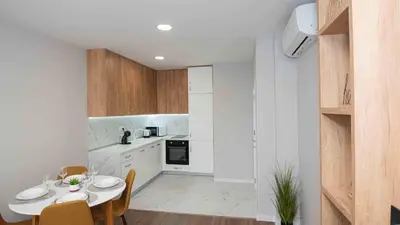 a kitchen with white cabinets and a table and chairs at Sea Holiday 21 in Burgas City