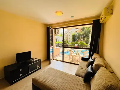 a living room with a couch and a tv and a balcony at KALIA C4 One Bedroom Apartment Sunny Beach in Sunny Beach
