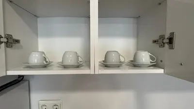a cabinet with four cups and saucers in it at ASTORIA II Apartment 24 One Bedroom in Elenite