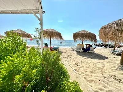 a beach with people sitting in chairs and umbrellas at Ipanema Beach - new - luxury first line - sea view in Sveti Vlas
