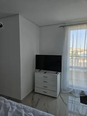 a bedroom with a tv on a dresser with a window at Ipanema Beach - new - luxury first line - sea view in Sveti Vlas