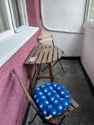 a wooden chair sitting in front of a window at Апартамент за гости Весела in Burgas City