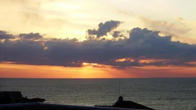 a sunset over the ocean with the sun setting at High in the Sky Apartments in Sozopol