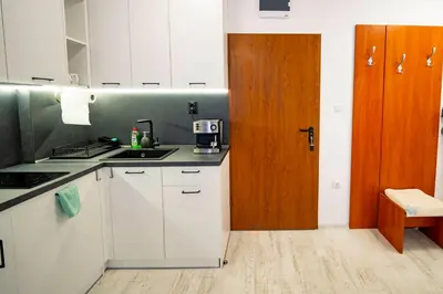 a kitchen with white cabinets and a wooden door at Harmani Haven 1BD Apartment with Own Parking spot by Flat Manаger in Sozopol