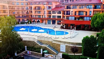 a swimming pool with chairs and umbrellas in front of buildings at Sky dreams Sveti Vlas in Sveti Vlas