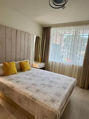 a bedroom with a bed with yellow pillows and a window at Domenico Luxury Apartments in Sunny Beach