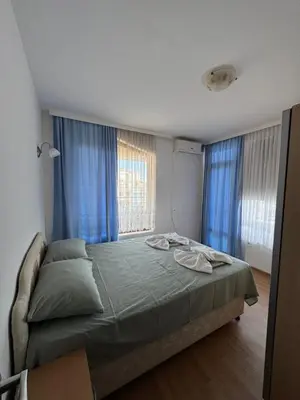 a bedroom with a large bed with blue curtains at VP Palazzo Nesebar in Nesebar