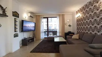 a living room with a couch and a flat screen tv at Premium Oasis Beach Club Apartment in Lozenets