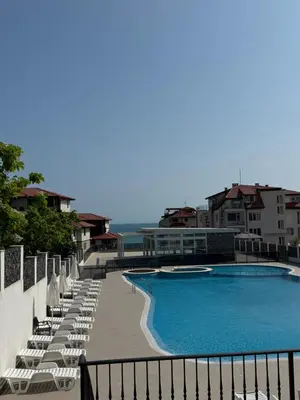 a swimming pool with chaises and chairs next to a building at Luxury seaside apartment with seaview in Sveti Vlas