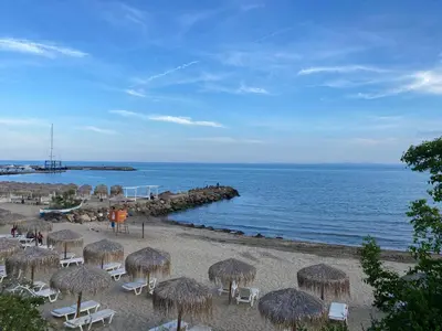 a beach with chairs and straw umbrellas and the ocean at Grand Villa luxury apartment with sea view in Sveti Vlas