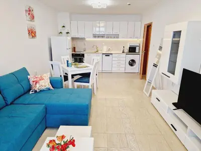 a living room with a blue couch and a kitchen at Diamond beach apartment in Sveti Vlas