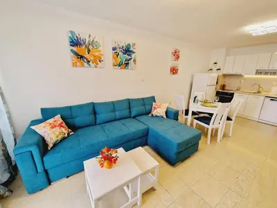 a living room with a blue couch and a kitchen at Diamond beach apartment in Sveti Vlas