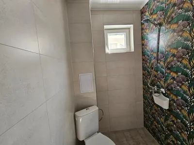 a bathroom with a toilet with a tropical wallpaper at Естрела къща за гости in Ravda