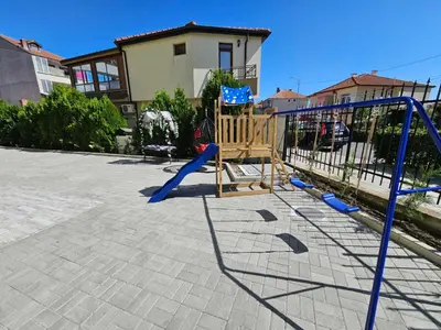a playground with a swing set in front of a building at Естрела къща за гости in Ravda