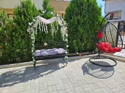 a swing in a garden with a bed at Естрела къща за гости in Ravda