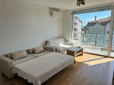 a living room with a couch and a large window at Modern Comfort Studio with Terrace Tsarevo in Tsarevo