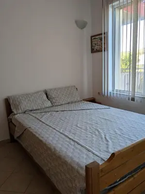 a bed in a bedroom with a large window at Akrotiri 2BR Apartment in Sozopol