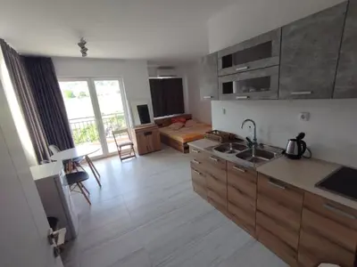 a kitchen with wooden cabinets and a living room at Studio Павлови Домус Екстра in Sveti Vlas