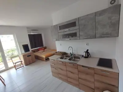 a kitchen with wooden cabinets and a living room at Studio Павлови Домус Екстра in Sveti Vlas
