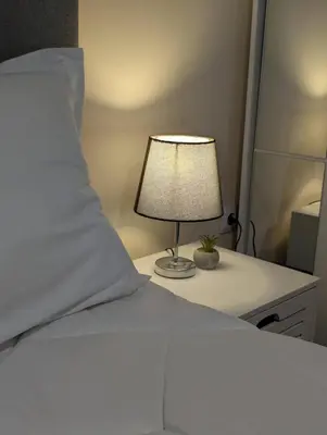 a bedroom with a bed with a lamp on a desk at Apartment Dimanov 1 in Burgas City