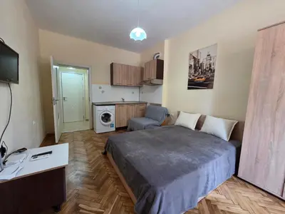 a small bedroom with a bed and a kitchen at Студио Слънчева перла in Burgas City