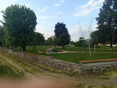 a park with a stone retaining wall and trees at Къща за гости Veranda Raia Поморие in Kamenar