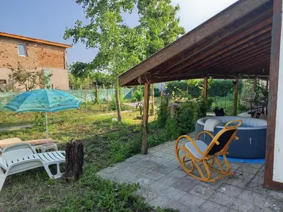 a patio with chairs and an umbrella and a tub at Къща за гости Veranda Raia Поморие in Kamenar