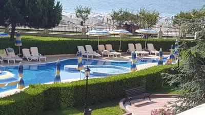 a swimming pool with chairs and umbrellas next to the ocean at Apartment Sunset resort C4-17 in Pomorie