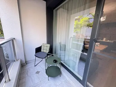 a small balcony with a chair and a table at Infinity Apartament in Burgas City