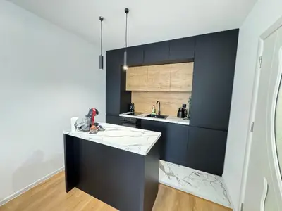a kitchen with black cabinets and a white counter top at Infinity Apartament in Burgas City